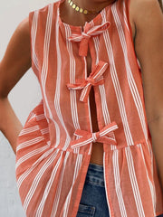 Orange and white striped peplum top with bow tie closures and a ruffled hem.