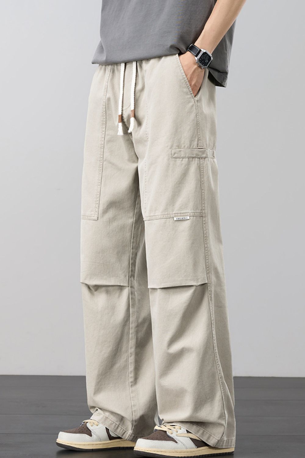 Beige cargo pants with adjustable drawstring and multiple pockets.