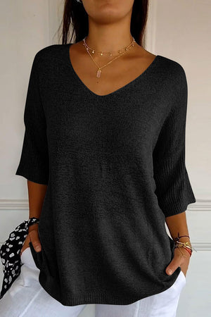 Black v-neck knit sweater with flared sleeves and a textured finish.