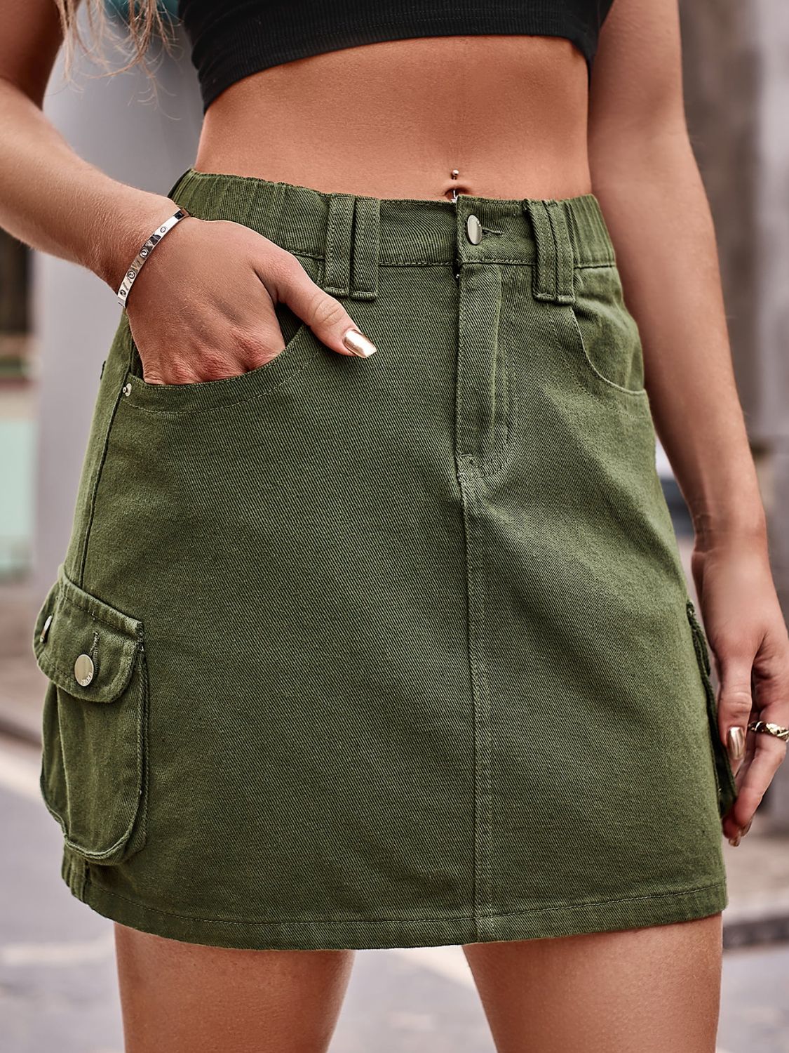 Army green denim mini skirt with cargo pockets and a button fly.