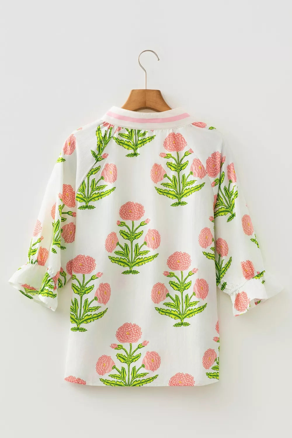 White cotton blouse with pink floral print and ruffled sleeves.