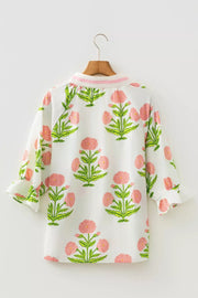 White cotton blouse with pink floral print and ruffled sleeves.