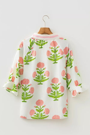 White cotton blouse with pink floral print and ruffled sleeves.