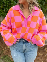Checkerboard button-up sweater in pink and orange with a collared neckline.