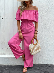 Hot pink off-the-shoulder ruffled jumpsuit with wide legs and elastic waist.