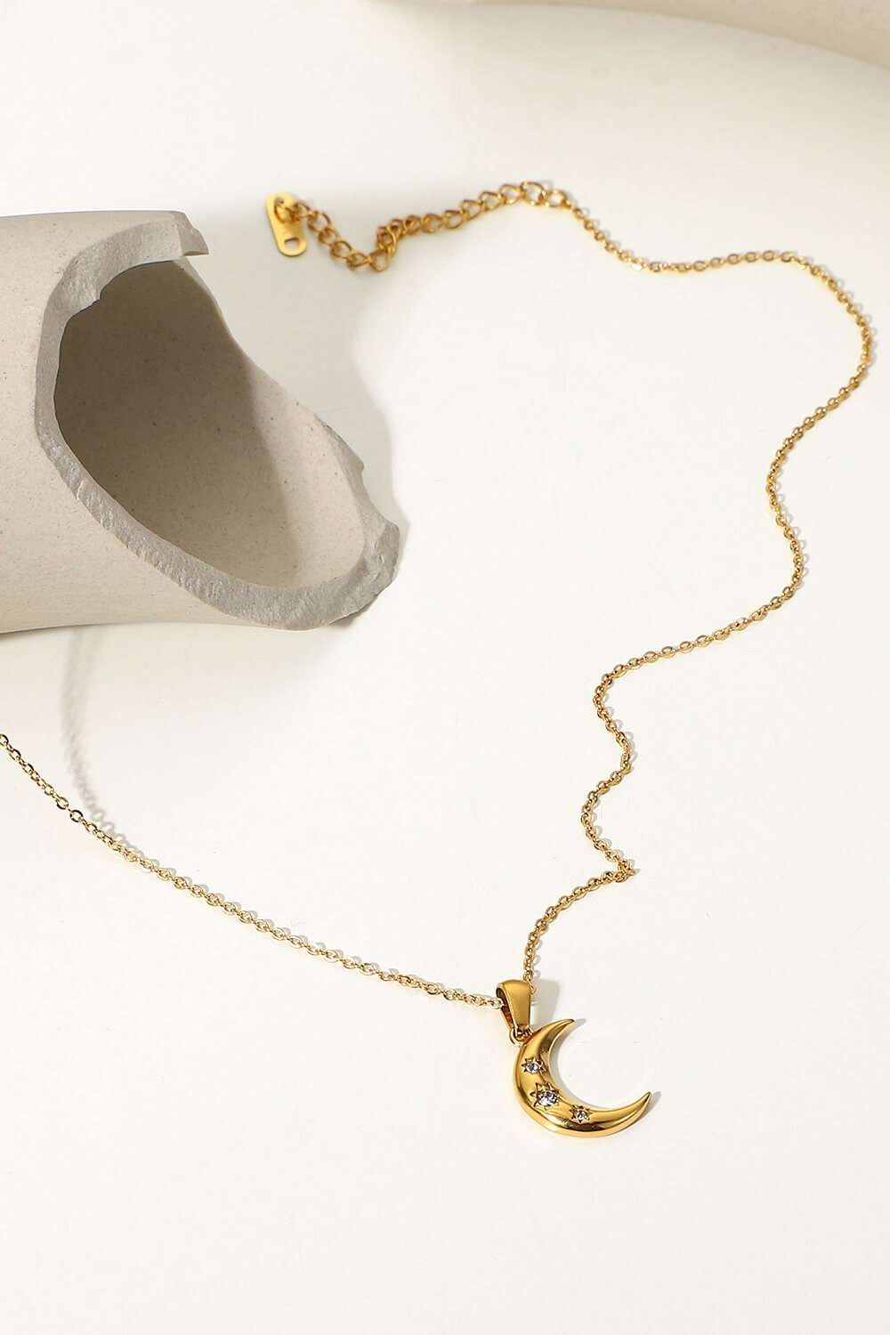 Gold crescent pendant necklace with clear stones on a delicate chain