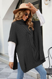 Black cable knit turtleneck poncho with side slits, acrylic.