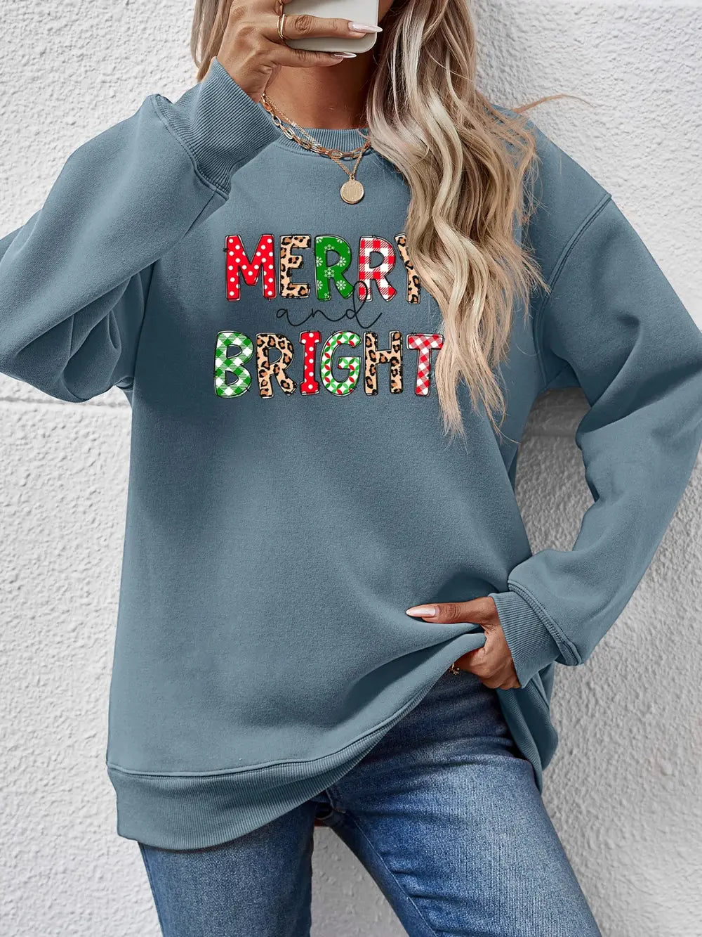 Light Blue crewneck sweatshirt with "Merry and Bright" graphic in festive patterns.