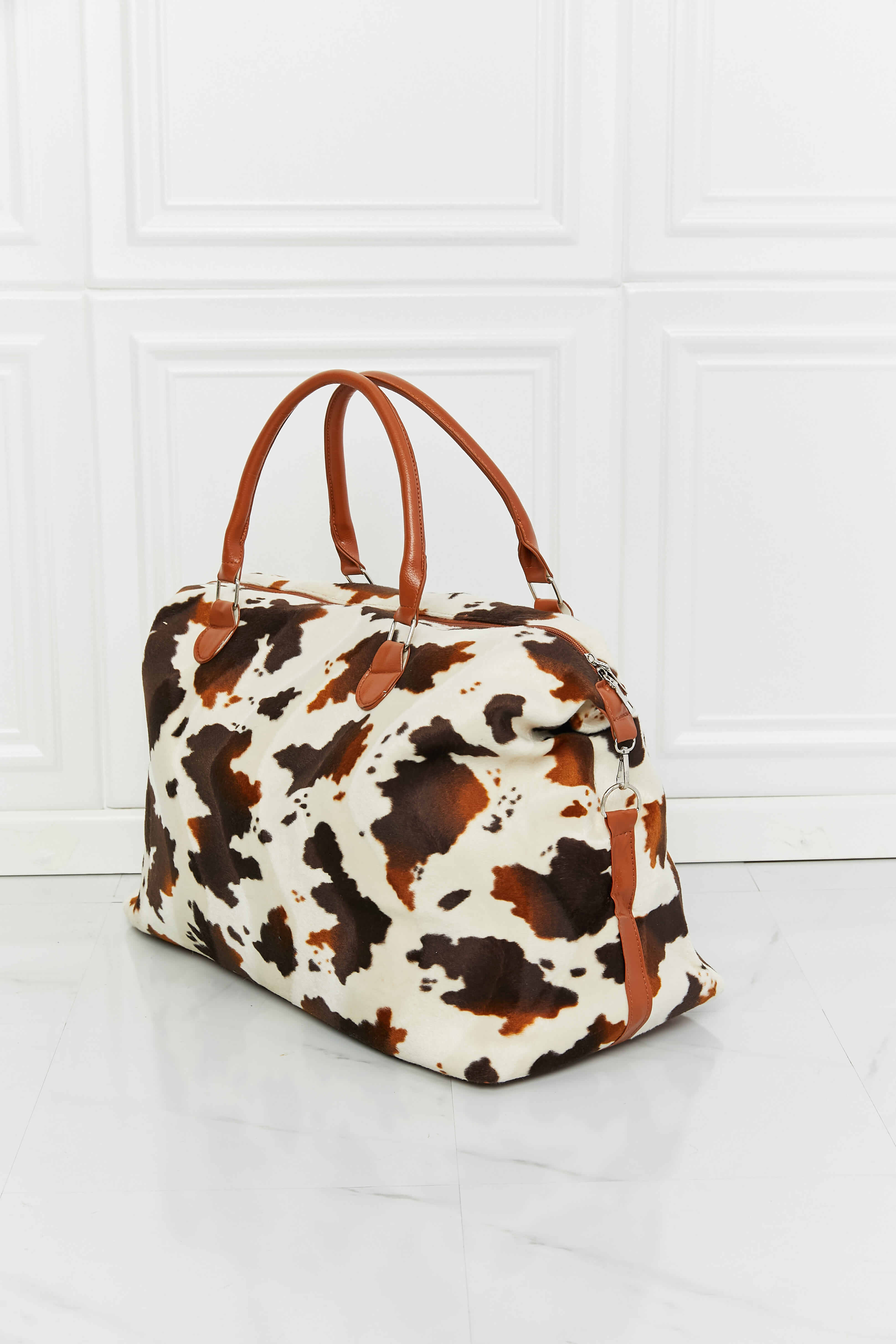 Cowhide print duffel bag with brown leather handles and trim