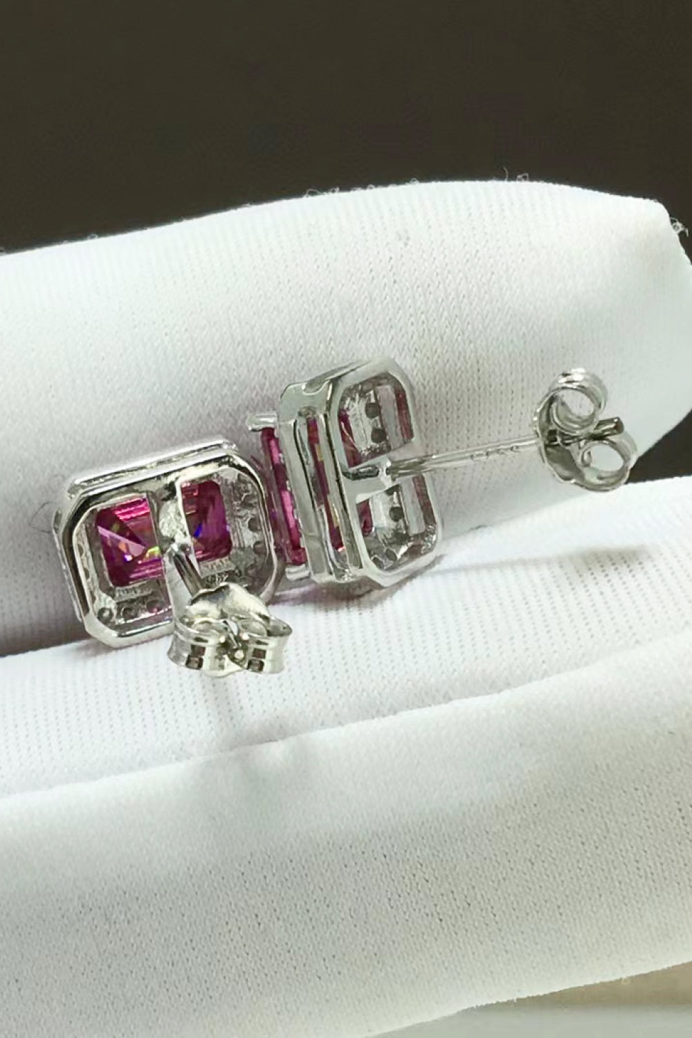 Emerald cut moissanite halo stud earrings in rose gold with diamond accents.