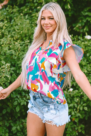 Abstract print blouse with ruffle sleeves and a V-neck, styled with distressed denim shorts.