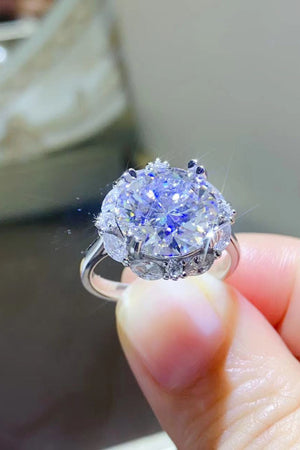 Silver moissanite halo ring with large center stone and smaller accent stones.