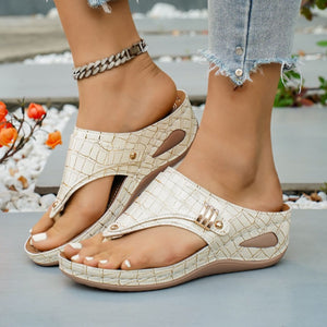 Beige crocodile-embossed wedge thong sandals with gold buckle detail.