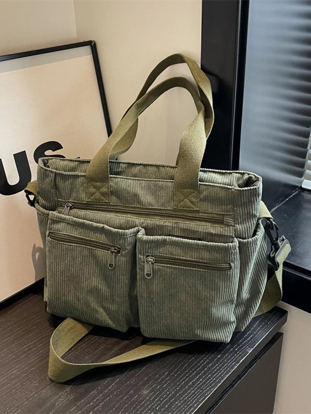 Green corduroy crossbody bag with multiple zippered pockets and adjustable strap.