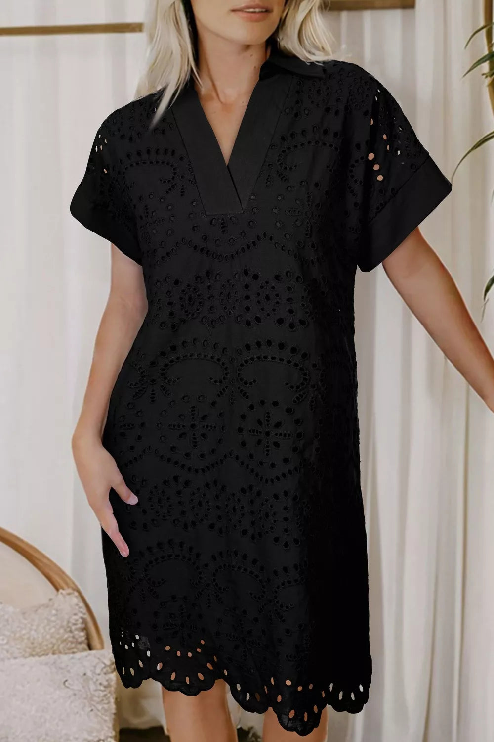 Black cotton dress with intricate eyelet details and V-neckline.