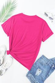 Neon pink t-shirt with rolled sleeves, knotted hem, and casual styling with denim shorts.