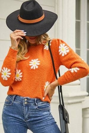 Orange textured knit sweater with daisy motif, crew neck, and long sleeves.