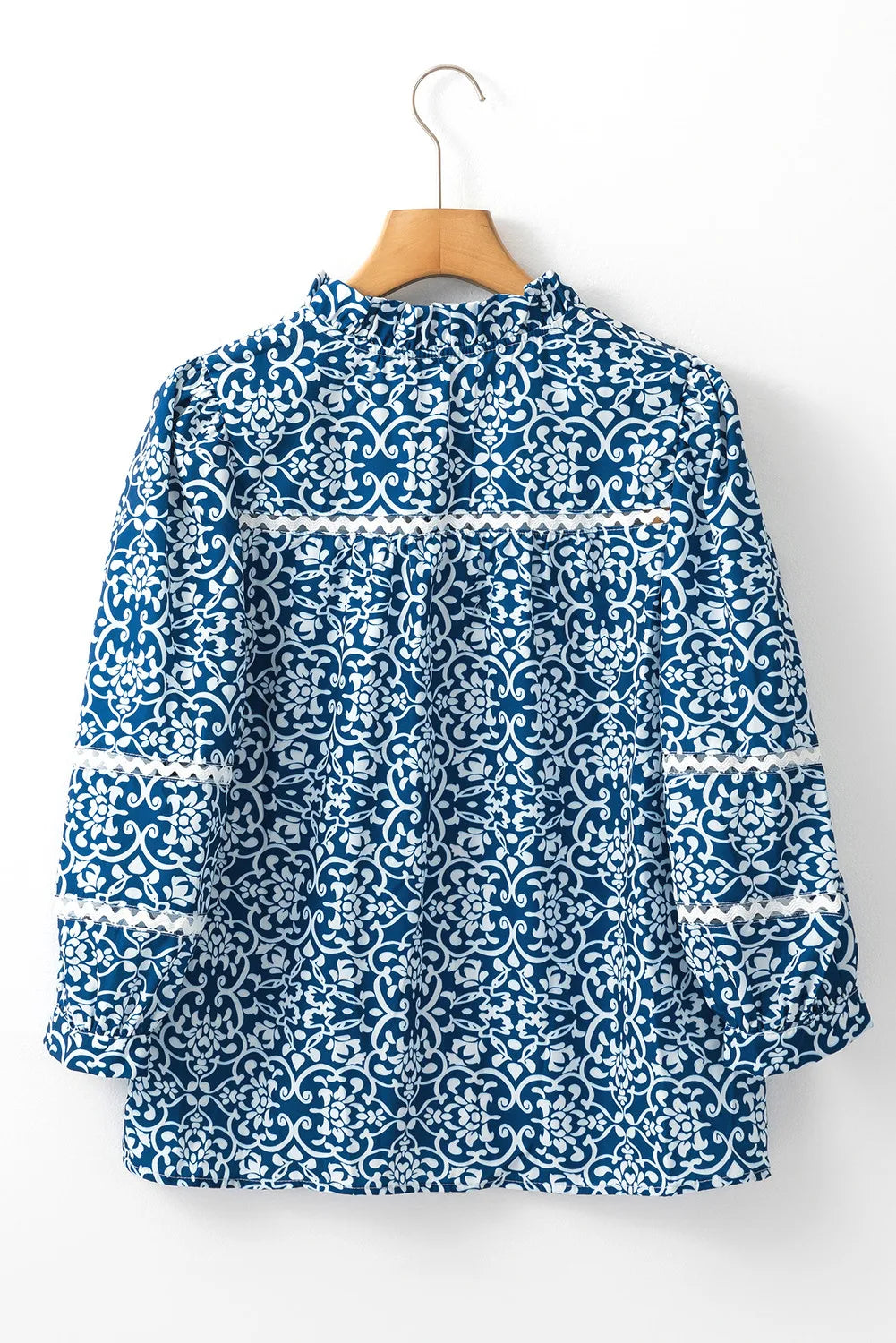 Indigo medallion print poet blouse with ruffled neckline and lace trim on sleeves.