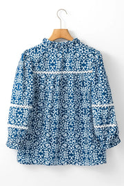 Indigo medallion print poet blouse with ruffled neckline and lace trim on sleeves.