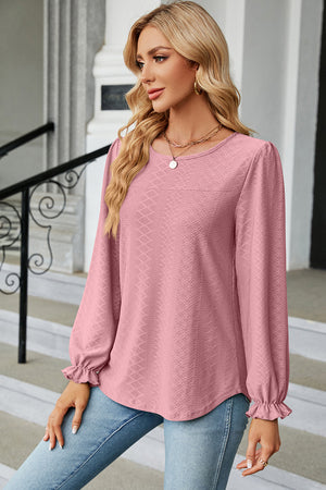 Blush pink textured puff sleeve blouse with ruffled cuffs and crew neck.