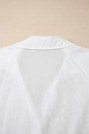 White embroidered eyelet blouse with a collared neckline and poet sleeves.