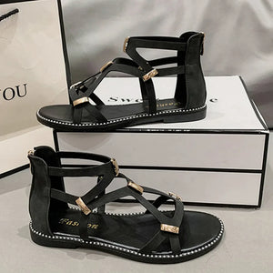 Black gladiator sandals with gold accents and zip-back closure.