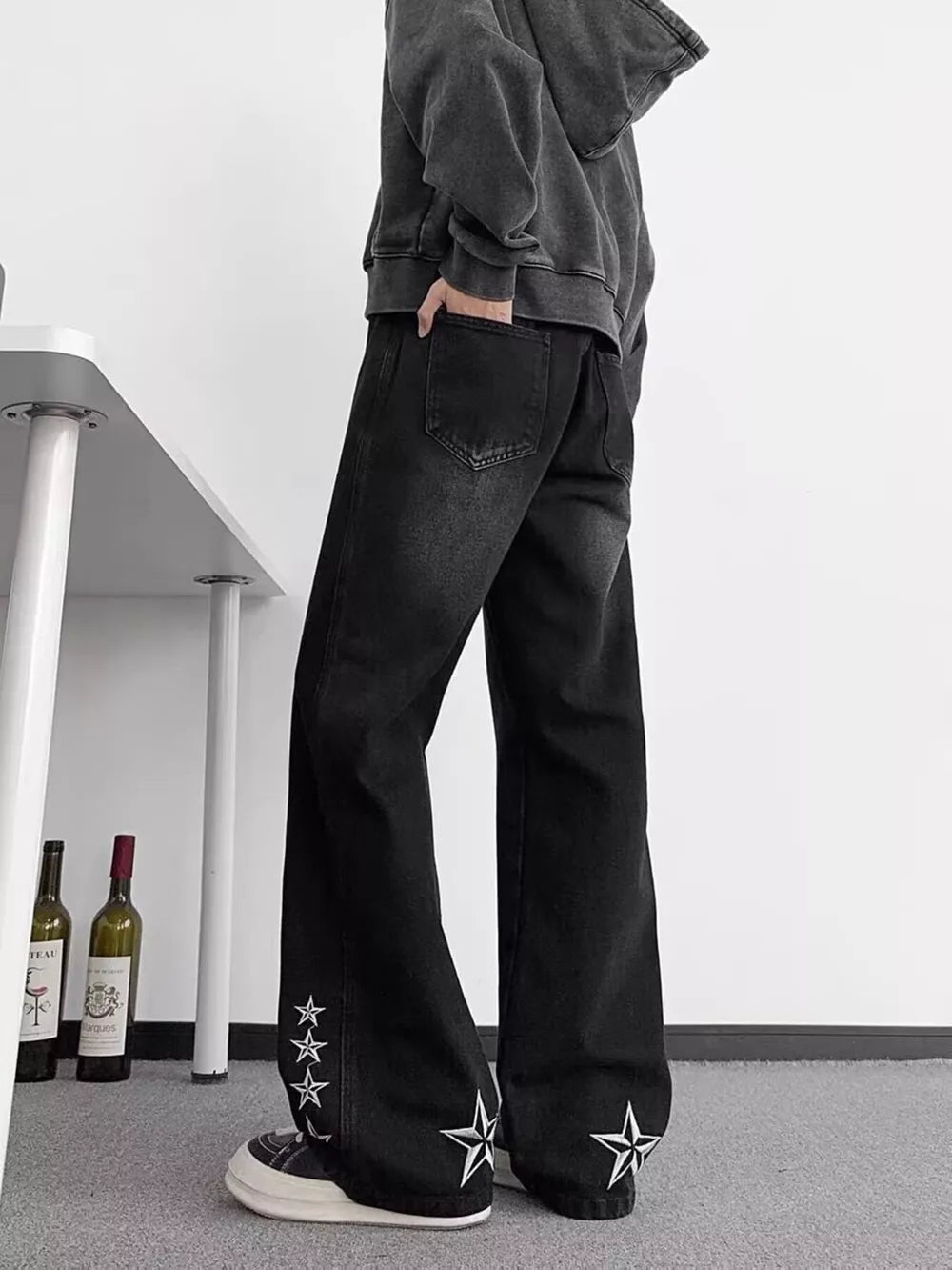 Black wide-leg men's jeans with star embroidery on the hems.