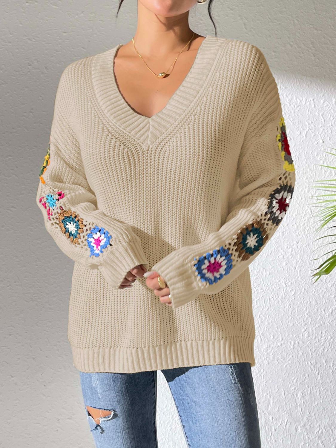 Tan v-neck sweater with colorful crochet granny square details on the sleeves.