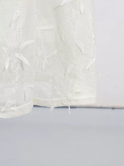 White midi dress with delicate floral appliques and textured fabric.