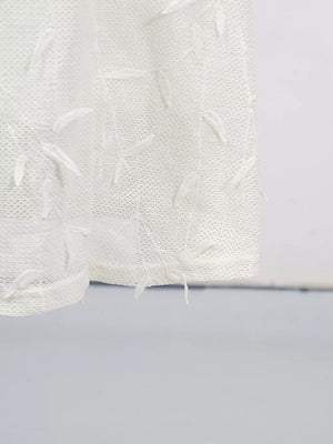 White midi dress with delicate floral appliques and textured fabric.