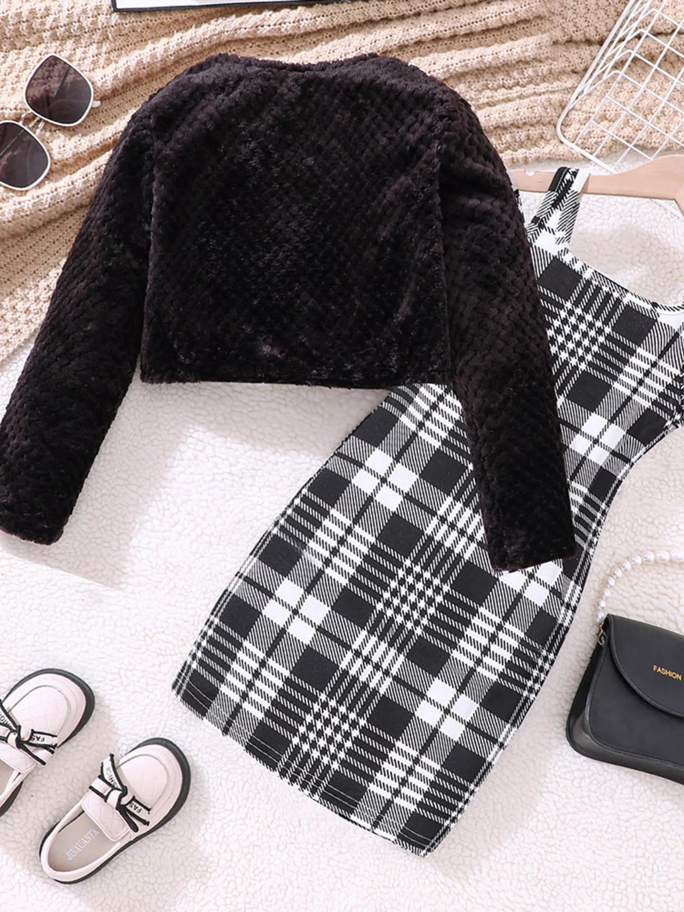 Black fuzzy cardigan with a plaid dress, a cozy outfit for babies.