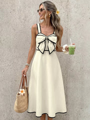 Elegant A-line midi dress in beige with black trim and a large bow detail on the bust.