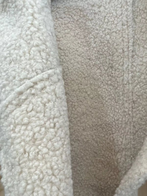 Cropped sherpa jacket in beige with fuzzy texture and pocket detail.