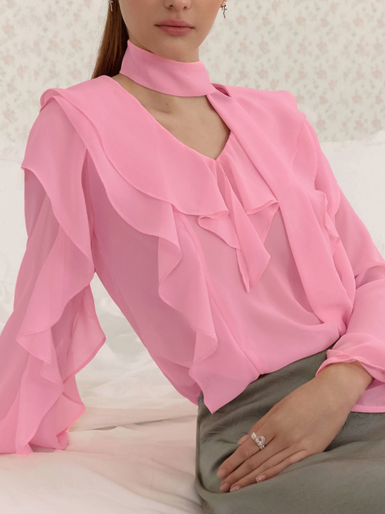 Pink chiffon blouse with V-neck, ruffle trim, and tie detail.