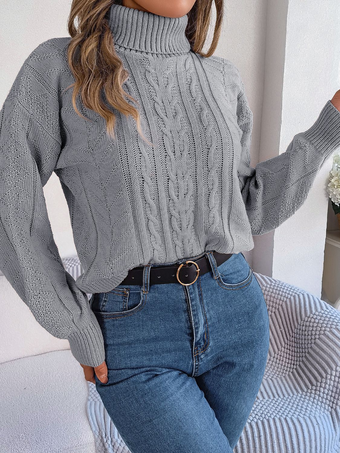 Light Gray cable knit turtleneck sweater with drop shoulder and textured sleeves.