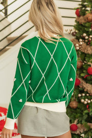 Green argyle knit sweater with white trim and pearl embellishments.