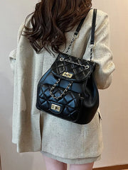 Black quilted mini backpack with chain straps and gold hardware.