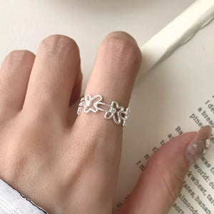 Sterling silver open ring with delicate floral motif and small clear stones.