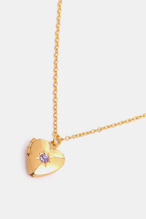 Gold heart locket necklace with purple gemstone and starburst detail.