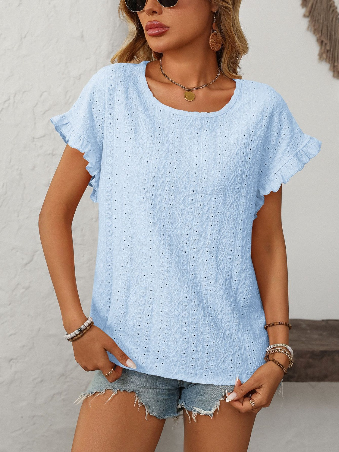 Light blue eyelet knit blouse with ruffled short sleeves and a scoop neckline.