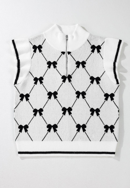 White knit zip vest with black diamond bow pattern, mock neck, and ruffled sleeves.