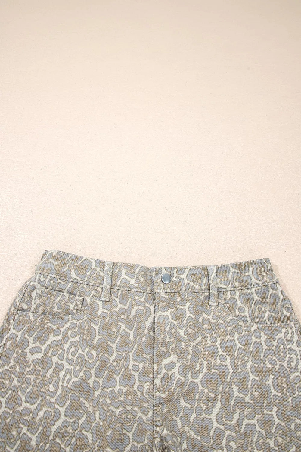Denim shorts with a subtle leopard print in grey and tan, featuring a button fly and front pockets.