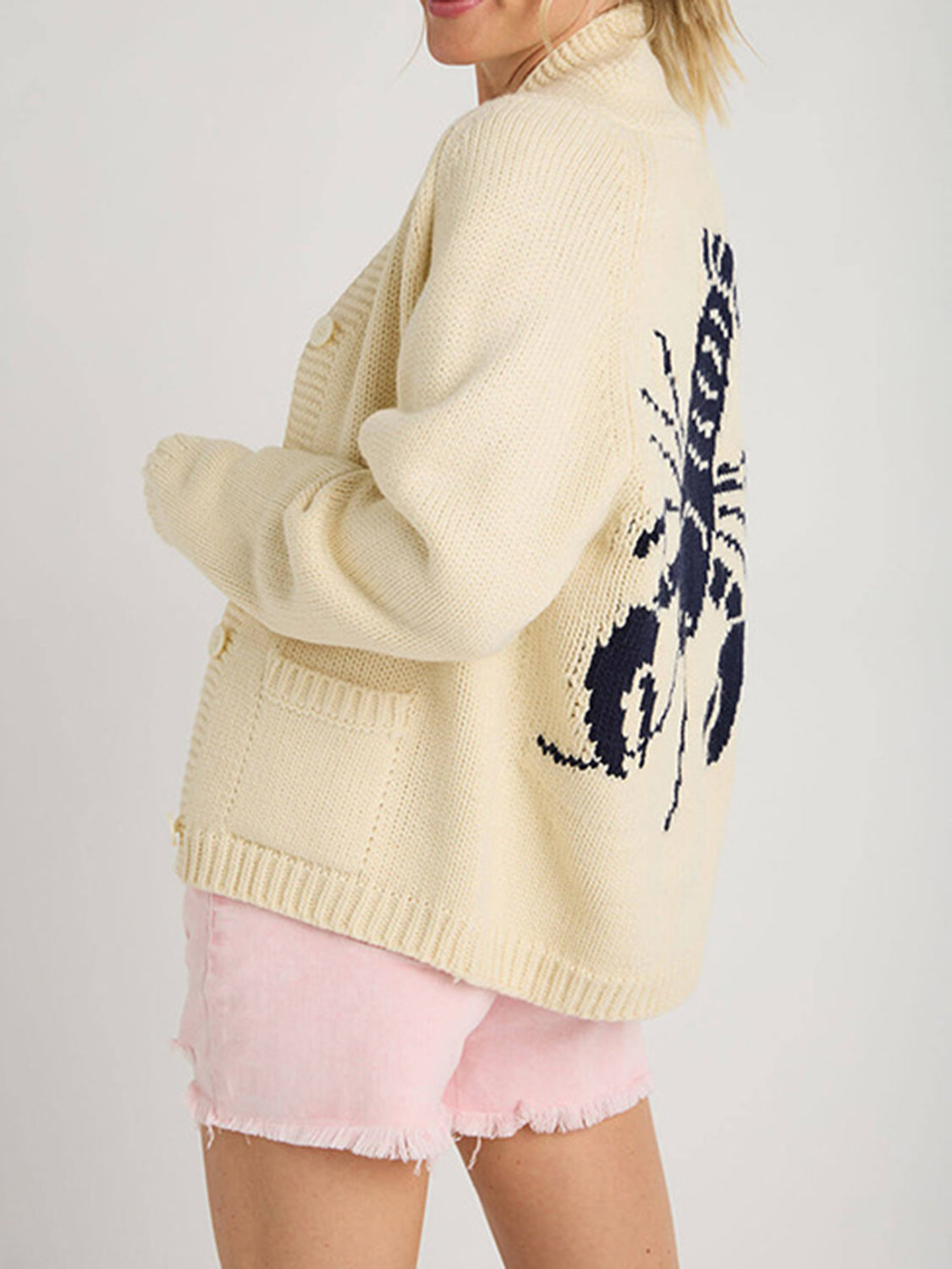 Cream knit cardigan with navy lobster appliqué on back, button front, and pockets.