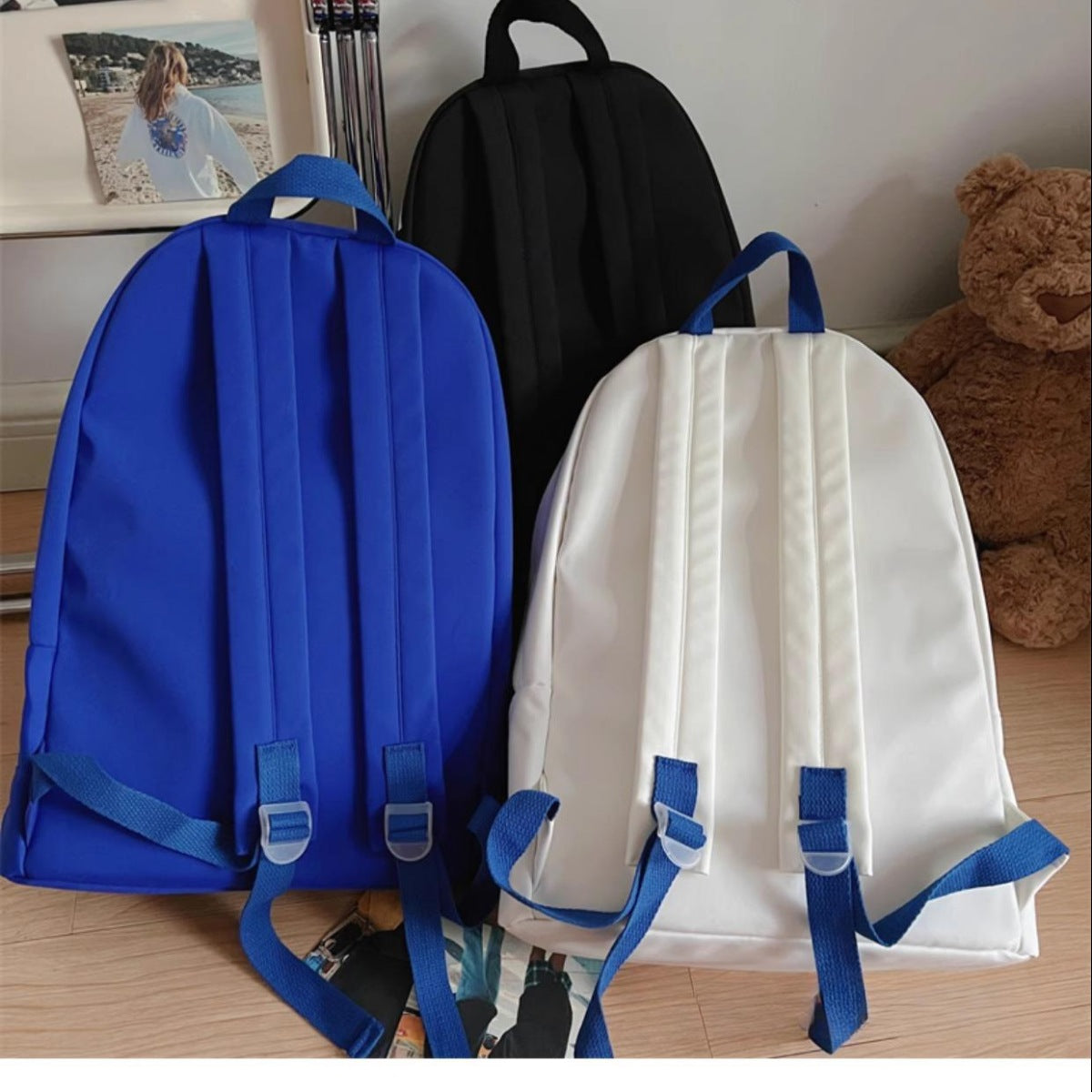 Nylon medium backpacks in black, off-white, and Klein blue with adjustable straps.