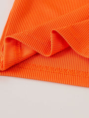 Orange ribbed cotton baby top detail with stitched hem and cuffs.