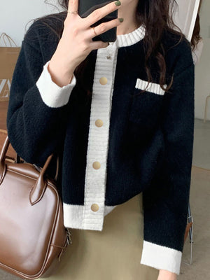 Black acrylic cardigan with white contrast trim and gold buttons.