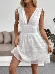 White textured smocked deep V-neck mini dress with tie shoulder straps and cinched waist.