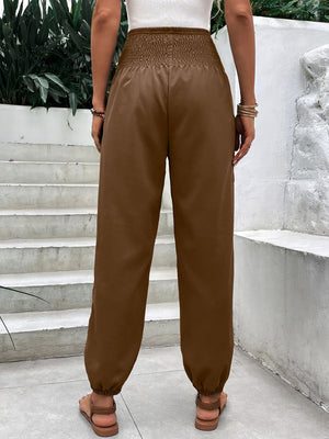Brown relaxed-fit trousers with smocked waistline and cinched ankles.