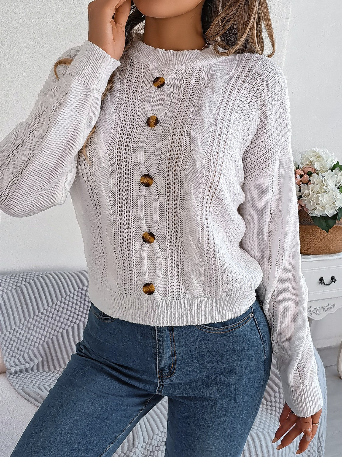 White cable knit button-up sweater with tortoise buttons and open knit details