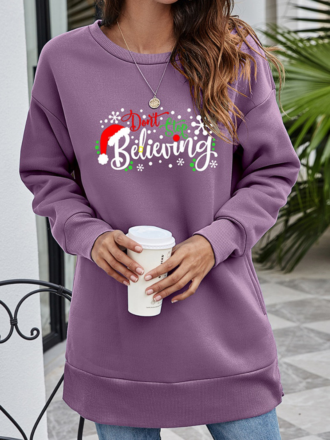 Purple graphic tunic sweatshirt with "Don't Stop Believing" holiday print and crew neck.